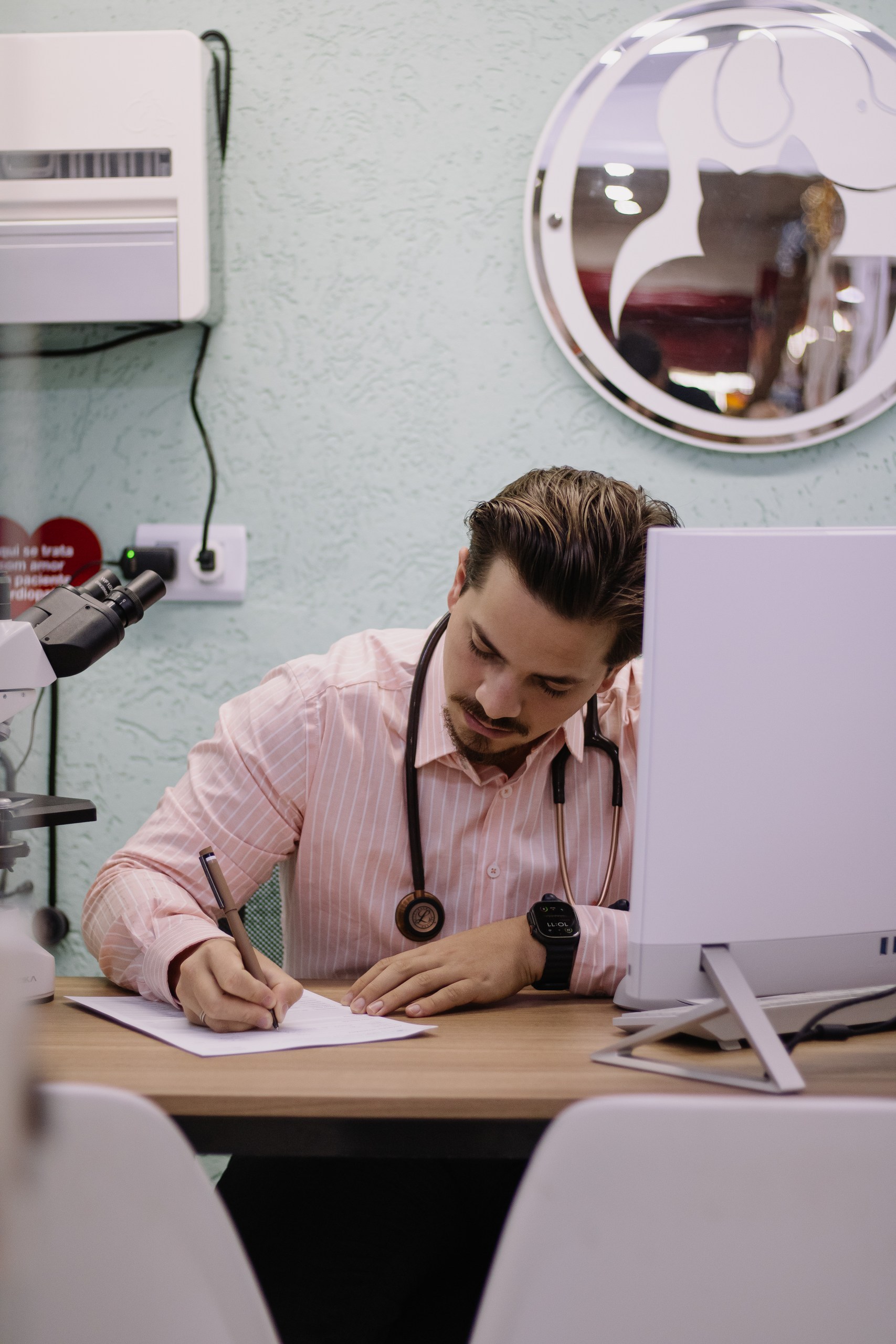 Dr. Guilherme registrando informações clínicas no consultório
